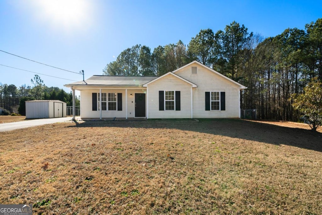 ranch-style home featuring covered porch, a shed, and a front lawn