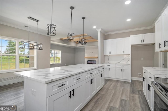 kitchen featuring light stone counters, decorative light fixtures, white cabinets, light hardwood / wood-style floors, and a kitchen island