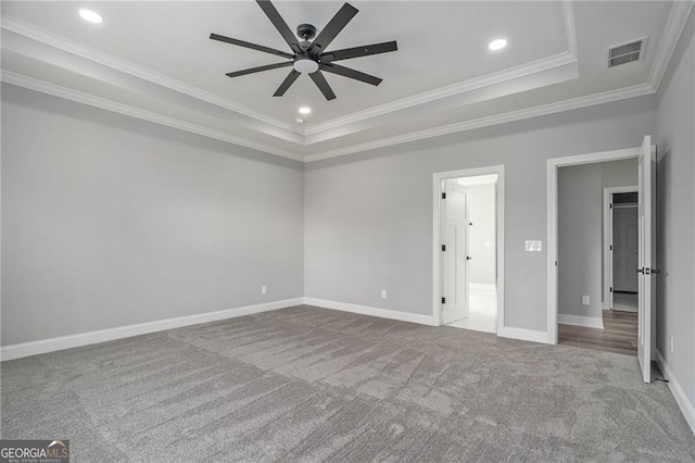 carpeted spare room with a tray ceiling, ceiling fan, and ornamental molding