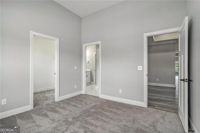 unfurnished bedroom featuring light carpet, a closet, a spacious closet, and a high ceiling