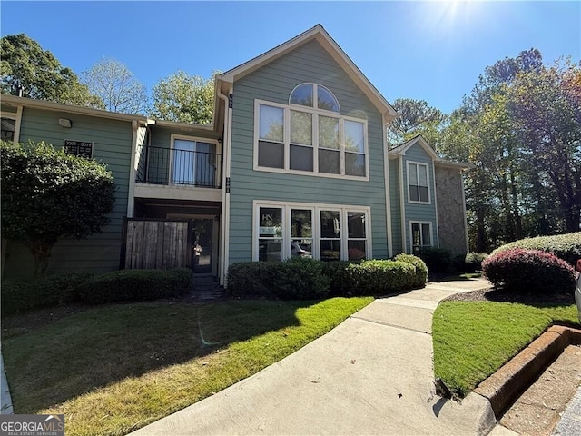 view of front of home with a balcony and a front lawn