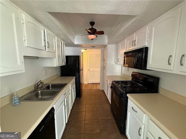 kitchen with a tray ceiling, white cabinetry, sink, and black appliances