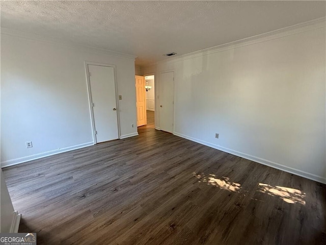 spare room with ornamental molding, a textured ceiling, and dark wood-type flooring