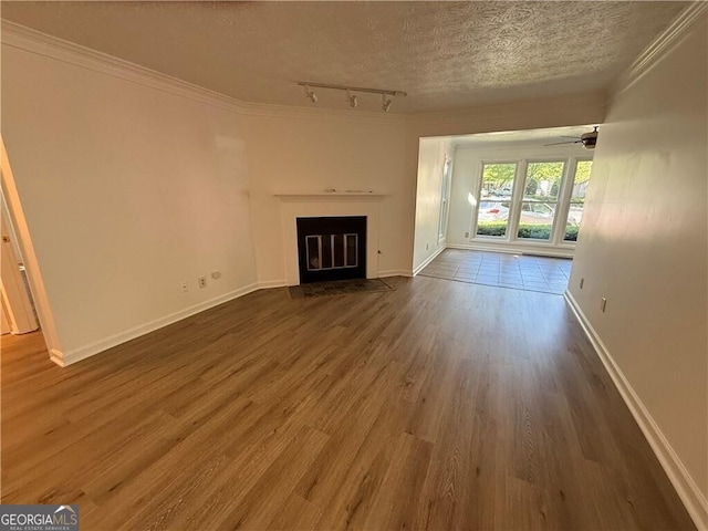 unfurnished living room with rail lighting, a textured ceiling, ceiling fan, crown molding, and hardwood / wood-style flooring