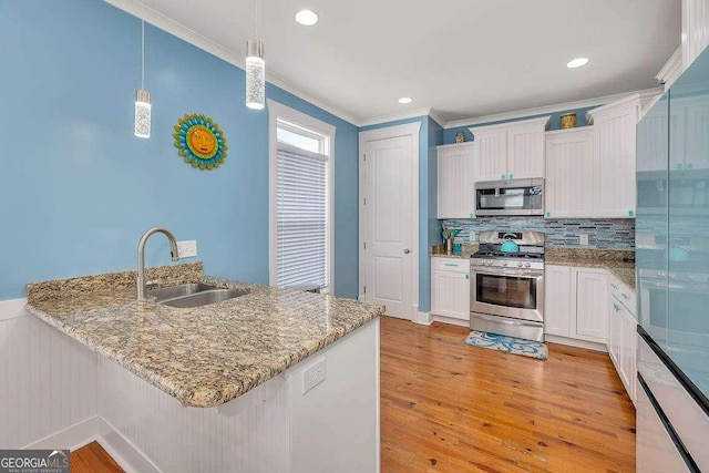 kitchen featuring white cabinetry, sink, pendant lighting, appliances with stainless steel finishes, and light wood-type flooring