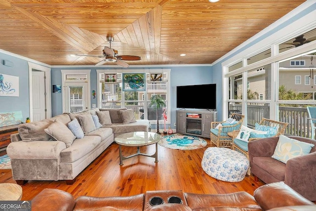 living room with wood ceiling, ceiling fan, crown molding, hardwood / wood-style flooring, and a fireplace