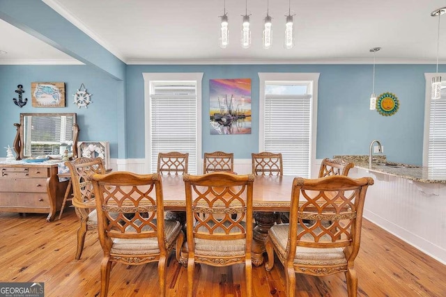 dining room with light wood-type flooring, sink, and ornamental molding