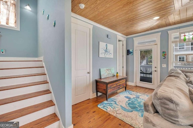 interior space with light wood-type flooring, wood ceiling, and ornamental molding