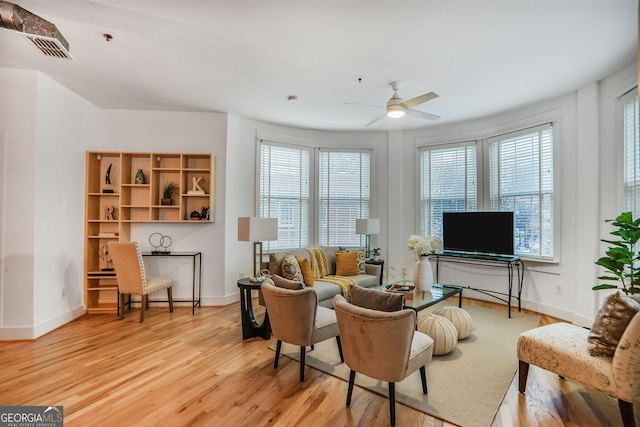 living room with plenty of natural light, light hardwood / wood-style floors, and ceiling fan