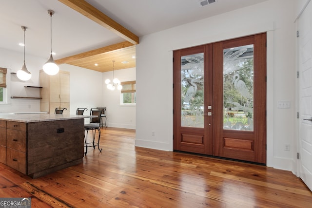 foyer with beam ceiling, french doors, dark wood-type flooring, and an inviting chandelier