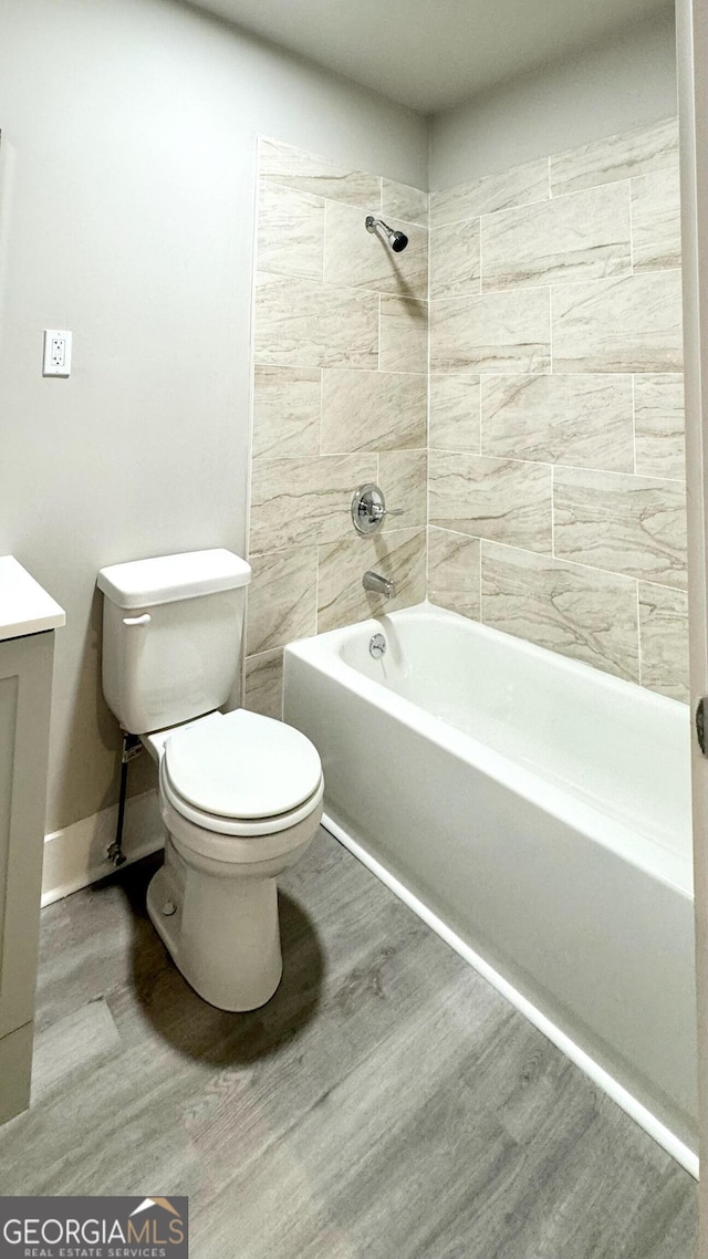 full bathroom with vanity, wood-type flooring, tiled shower / bath combo, and toilet