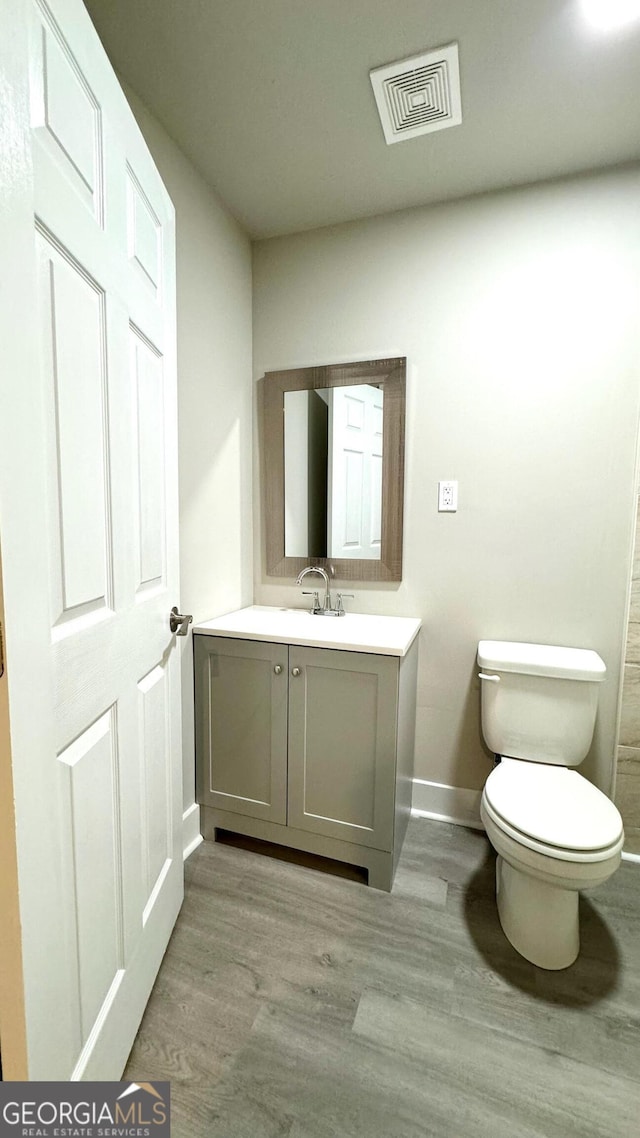 bathroom with wood-type flooring, vanity, and toilet