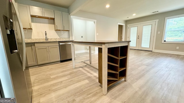 kitchen featuring tasteful backsplash, light wood-type flooring, stainless steel appliances, and french doors