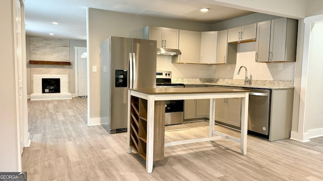 kitchen featuring a fireplace, gray cabinets, light hardwood / wood-style floors, and stainless steel appliances