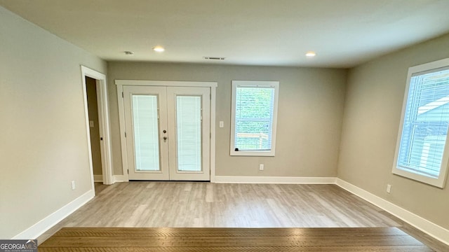 unfurnished room with french doors and light wood-type flooring