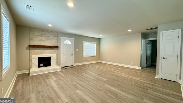 unfurnished living room with light hardwood / wood-style floors, a fireplace, and a wealth of natural light