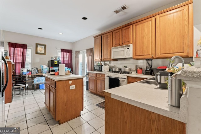 kitchen with light tile patterned floors, white appliances, tasteful backsplash, and a kitchen island