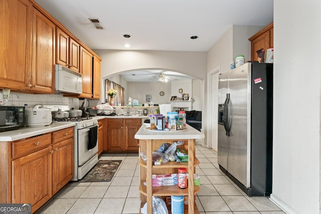 kitchen featuring tasteful backsplash, ceiling fan, light tile patterned floors, and white appliances