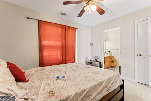 carpeted bedroom with ensuite bath and ceiling fan