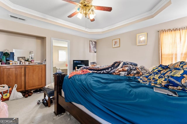 carpeted bedroom with a tray ceiling, ceiling fan, and ornamental molding