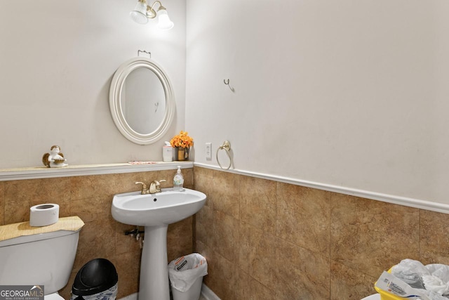 bathroom with toilet and tile walls