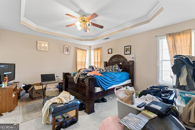 bedroom featuring ceiling fan, crown molding, light carpet, and a tray ceiling