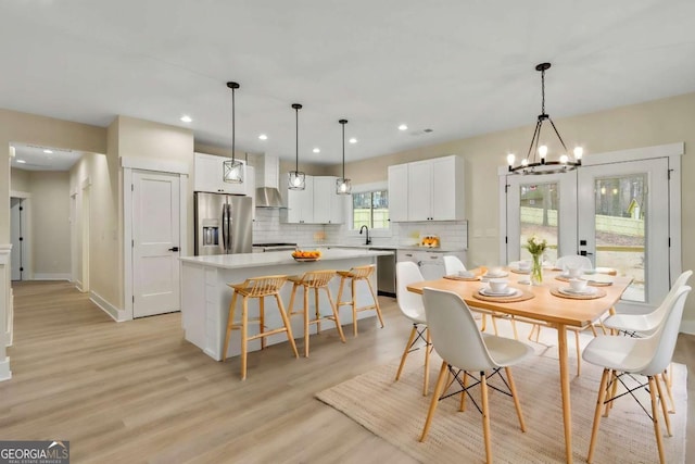 dining area featuring french doors, light wood-type flooring, sink, and a chandelier