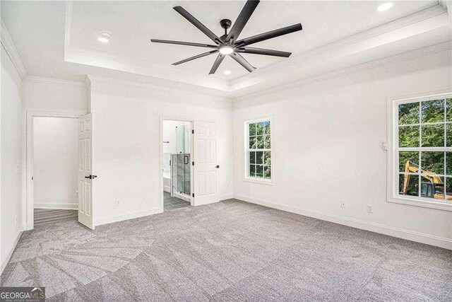 unfurnished bedroom with ornamental molding, a tray ceiling, ceiling fan, and light colored carpet