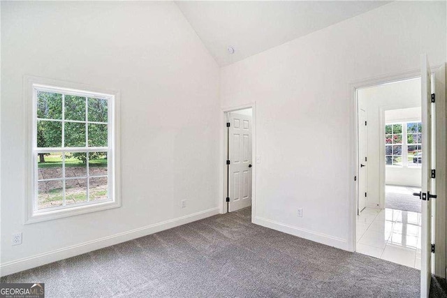 carpeted spare room with plenty of natural light and high vaulted ceiling