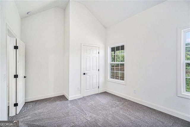 carpeted spare room featuring vaulted ceiling and a healthy amount of sunlight