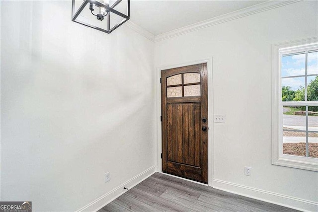 entrance foyer with light wood-type flooring, a notable chandelier, and ornamental molding