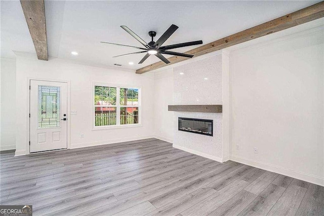 unfurnished living room featuring beamed ceiling, light hardwood / wood-style flooring, and ceiling fan