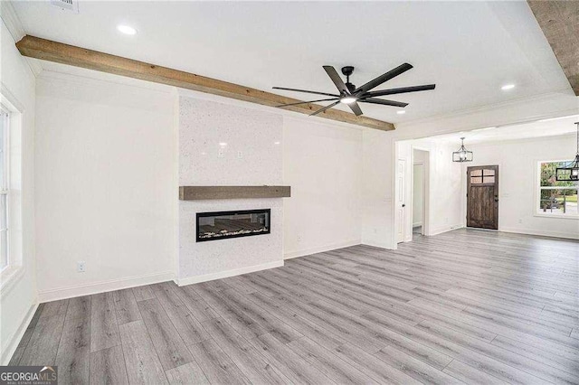 unfurnished living room with ceiling fan, a fireplace, beamed ceiling, and light hardwood / wood-style floors