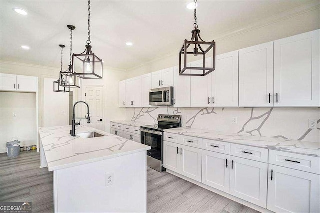 kitchen featuring a center island with sink, sink, hanging light fixtures, white cabinetry, and stainless steel appliances