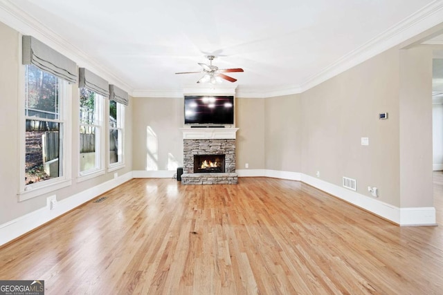 unfurnished living room featuring a fireplace, light hardwood / wood-style flooring, ceiling fan, and crown molding