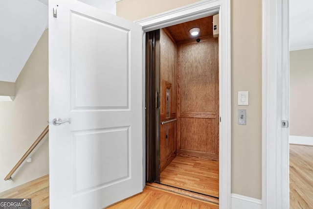 hall featuring elevator and light hardwood / wood-style flooring