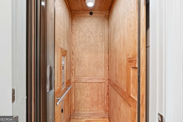 interior details with wooden walls, elevator, and wooden ceiling