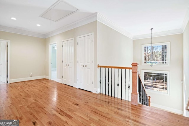 spare room with hardwood / wood-style floors, an inviting chandelier, and ornamental molding