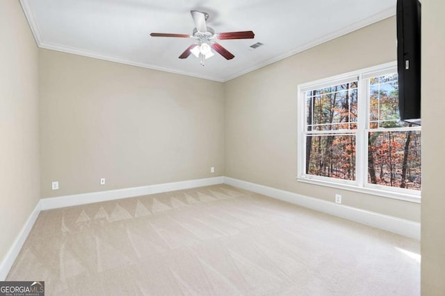 empty room featuring ceiling fan, light colored carpet, and ornamental molding