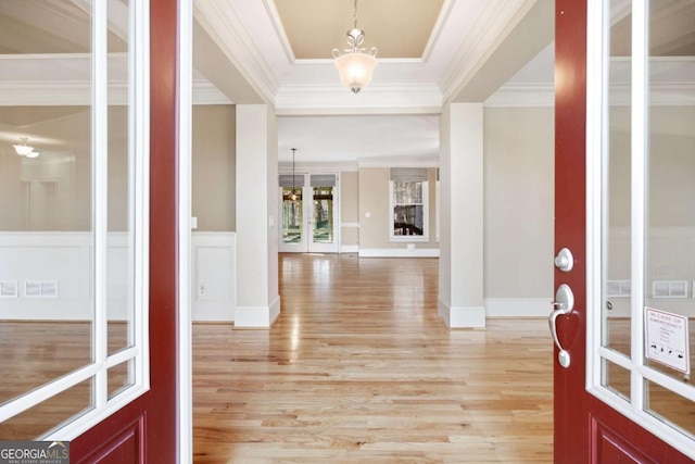 foyer featuring a notable chandelier, ornamental molding, and light hardwood / wood-style flooring