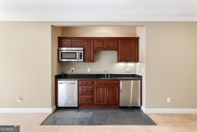 kitchen with crown molding, dark carpet, sink, and stainless steel appliances