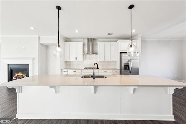 kitchen with a breakfast bar, wall chimney range hood, stainless steel fridge with ice dispenser, hanging light fixtures, and a large island