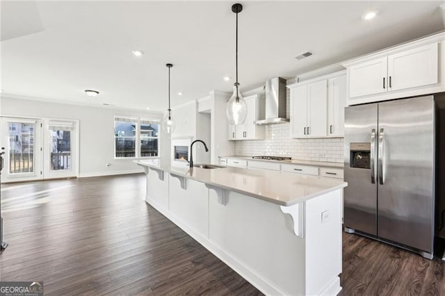 kitchen featuring white cabinets, hanging light fixtures, wall chimney exhaust hood, and stainless steel appliances