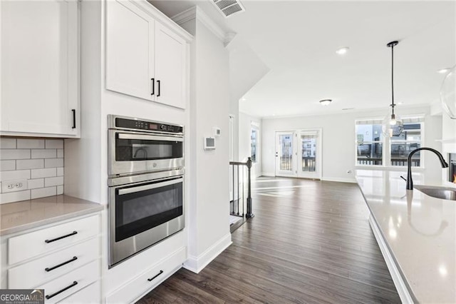 kitchen with tasteful backsplash, sink, white cabinets, and stainless steel double oven