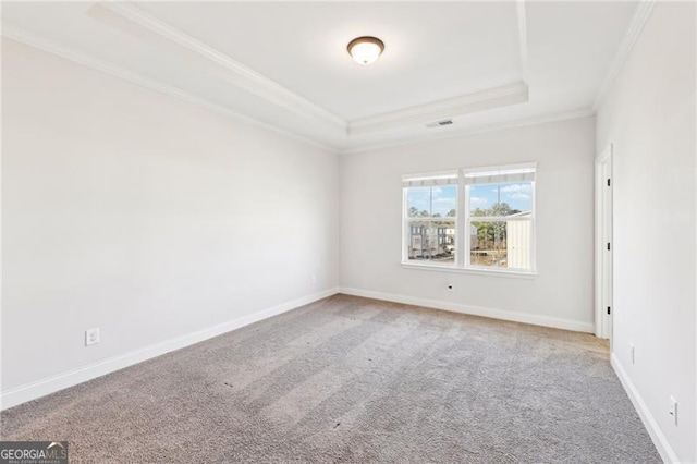 carpeted empty room featuring a raised ceiling and ornamental molding