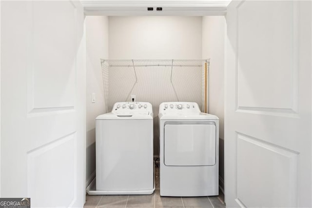 laundry area with washing machine and clothes dryer and light tile patterned floors