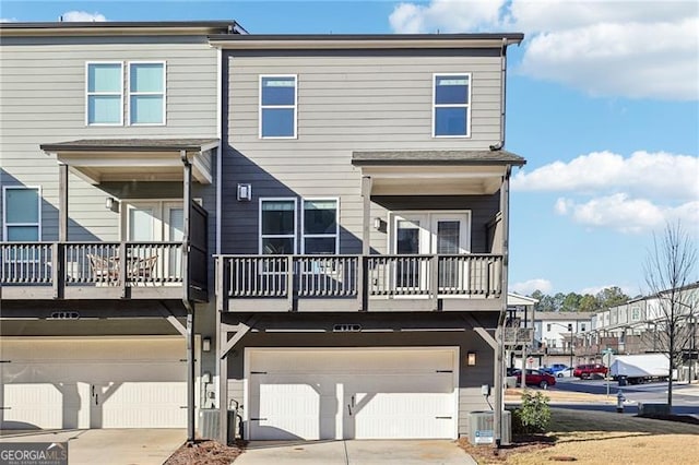 rear view of property featuring central AC unit and a garage