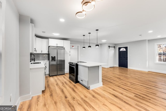 kitchen featuring a center island, stainless steel refrigerator with ice dispenser, a barn door, black / electric stove, and white cabinetry