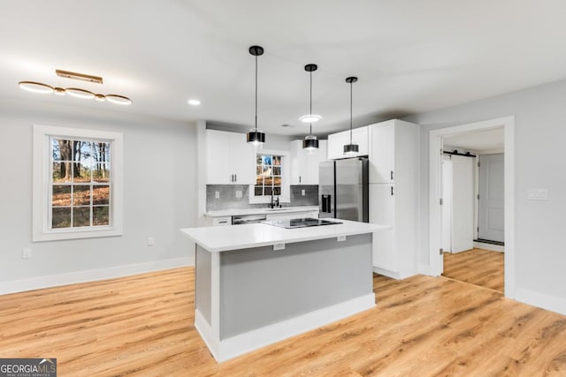 kitchen with tasteful backsplash, a barn door, a center island, and appliances with stainless steel finishes