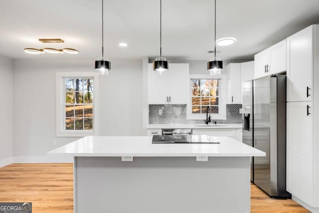 kitchen with backsplash, stainless steel appliances, sink, a center island, and white cabinetry